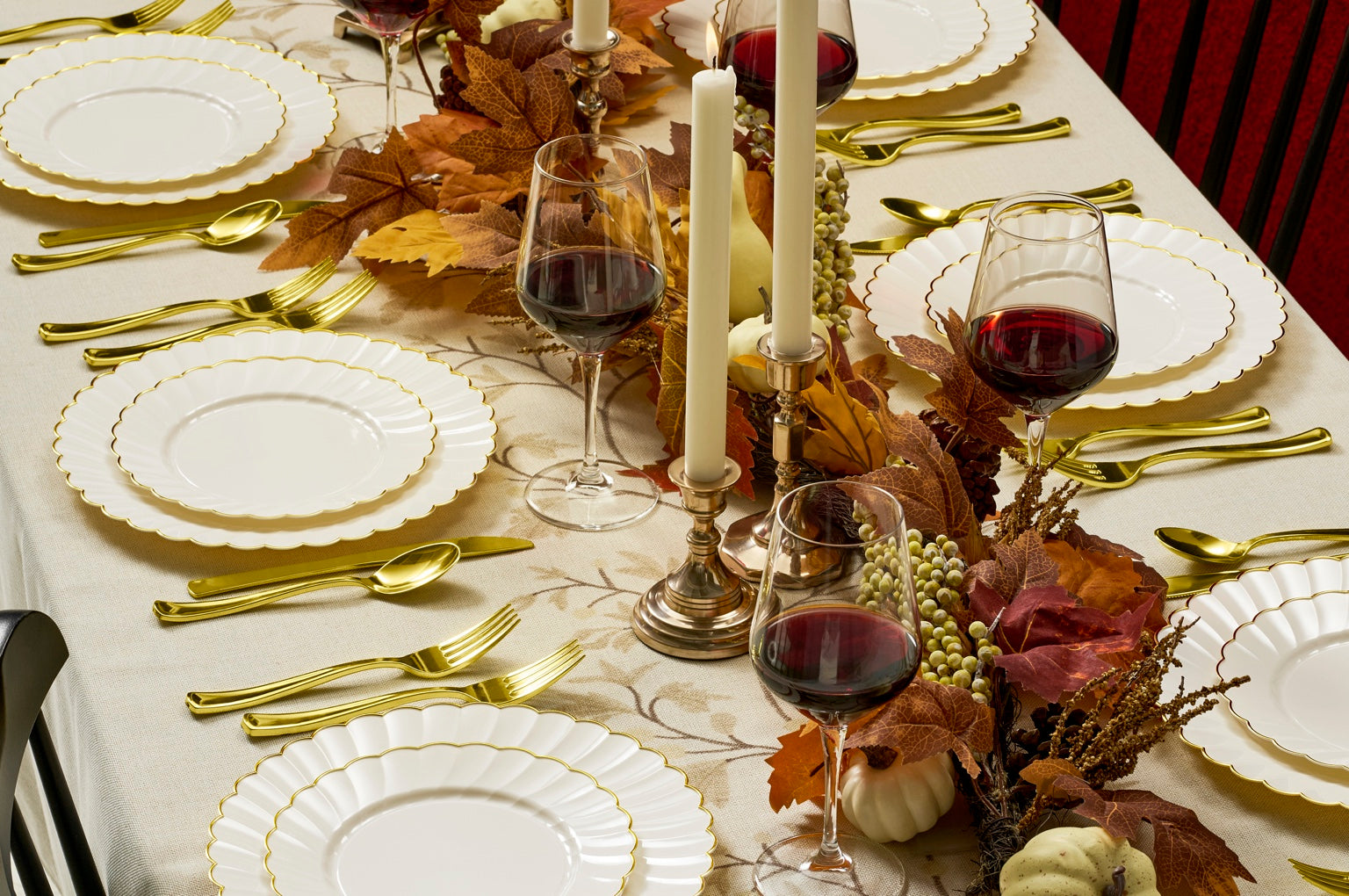 Elegant Thanksgiving table setting with ivory and gold scalloped disposable dinnerware, real wine glasses, candles and autumn decor